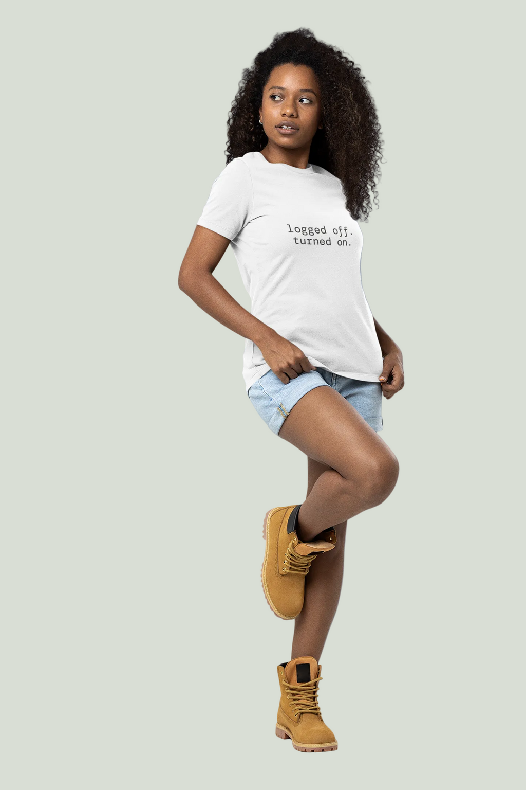 A young woman posing in a white graphic t-shirt with the text 'logged off. turned on.