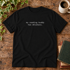 Black tee with my reading buddy has whiskers text in rustic flat lay