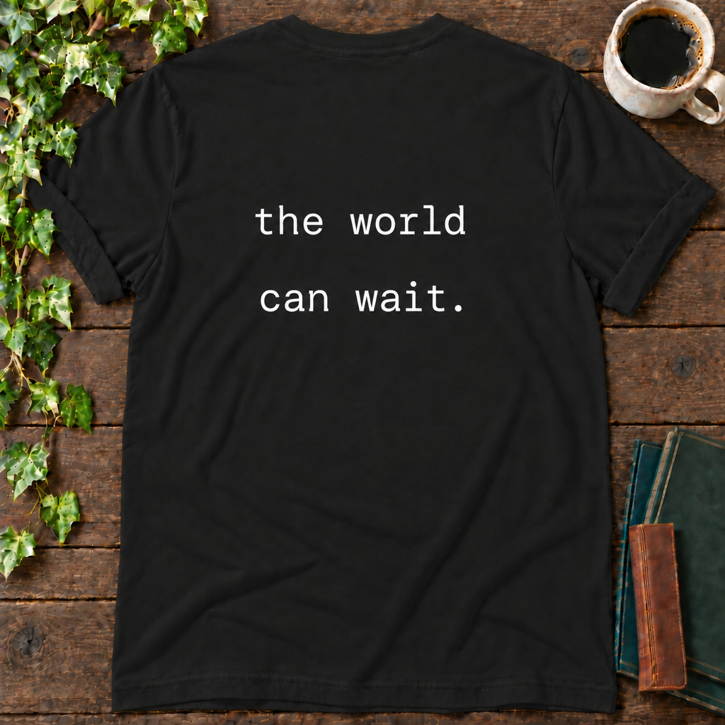 the world can wait. black t-shirt back print flat lay