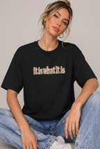Seated model wearing the it is what it is colourful t-shirt in Black