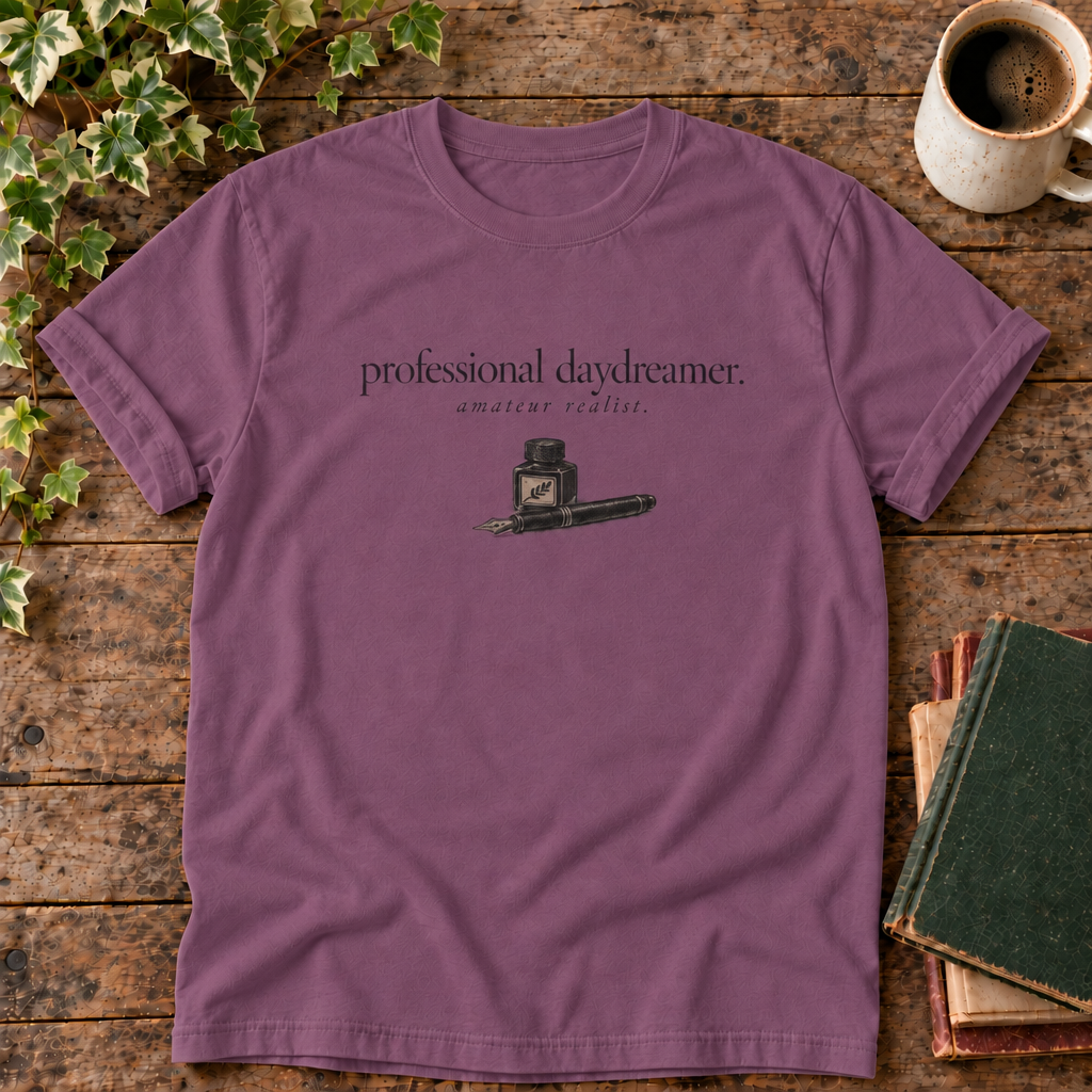 professional daydreamer t-shirt in Berry, flat lay on dark rustic wood with ivy, coffee mug and green-over-red-and-tan book pile