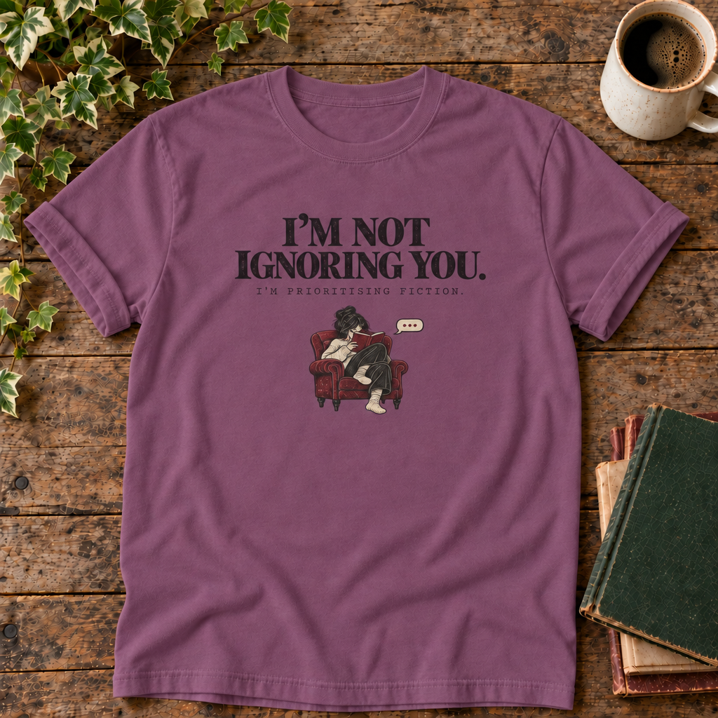 I'm not ignoring you t-shirt in Berry, flat lay on dark rustic wood with ivy, coffee mug and green-over-red-and-tan book pile