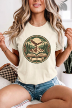 Seated blonde model in denim shorts wearing mountain adventure vintage t-shirt in Ivory