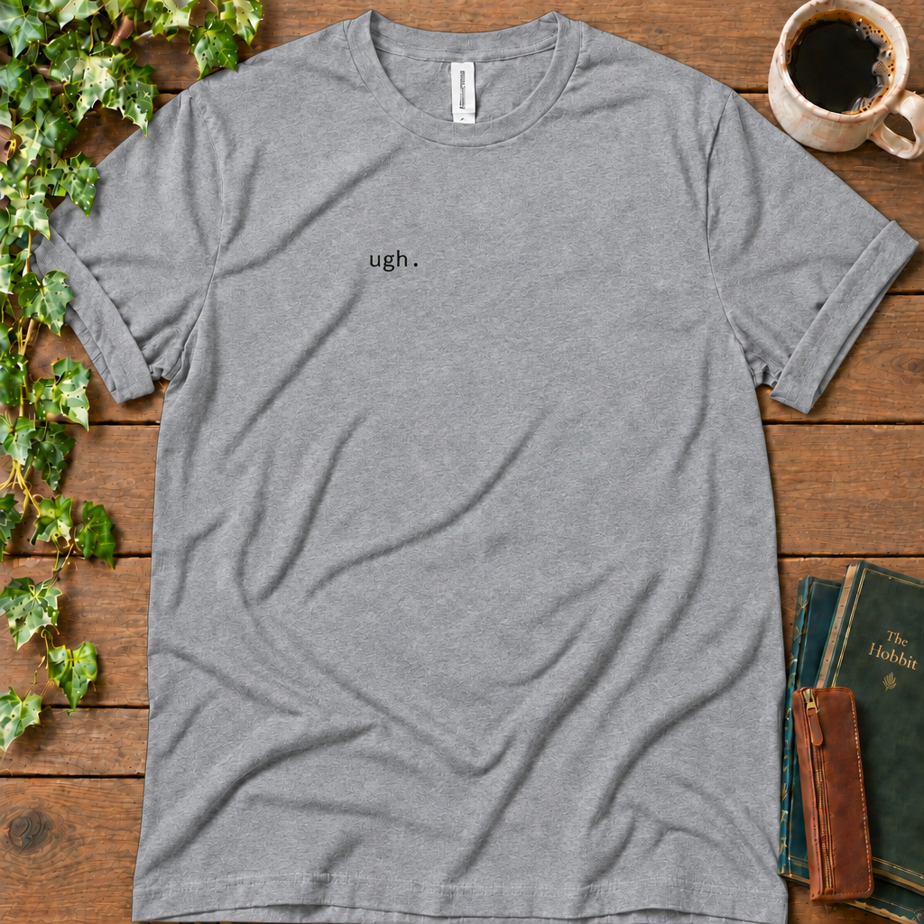 Athletic heather regular-fit tee printed with ugh. on the left chest, flat lay on rustic wood with ivy, coffee and vintage books