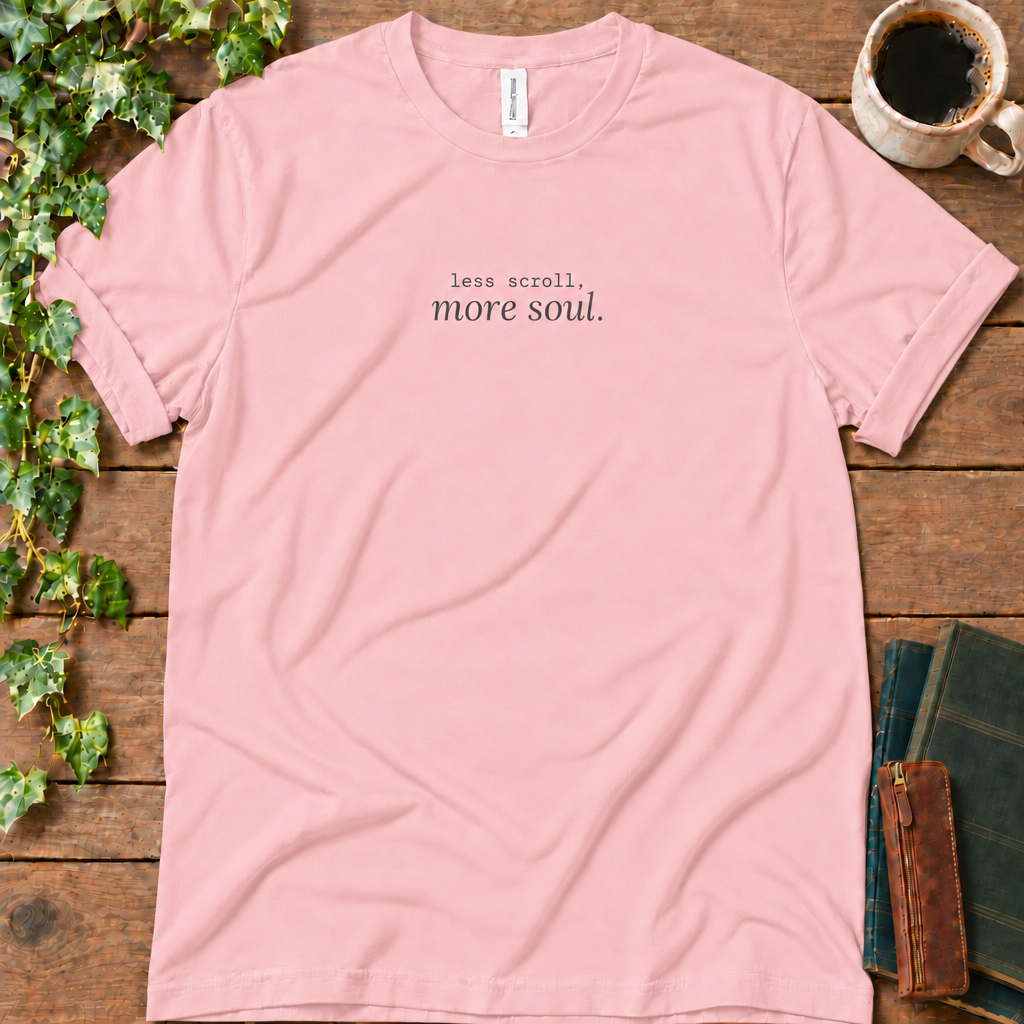Pink regular-fit tee printed with less scroll, more soul., flat lay on rustic wood with ivy, coffee and vintage books
