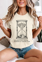 Seated blonde model in denim shorts wearing hourglass reading t-shirt in Ivory