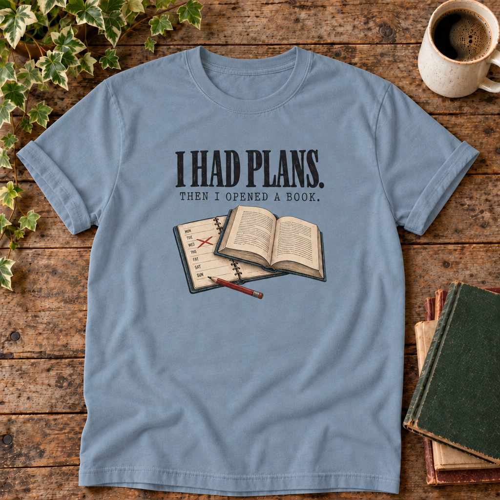 I had plans t-shirt in Blue Jean, flat lay on dark rustic wood with ivy, coffee mug and green-over-red-and-tan book pile
