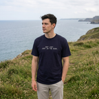 Man looking towards the sea wearing Not lost just in the book T-shirt in True Navy, front print visible