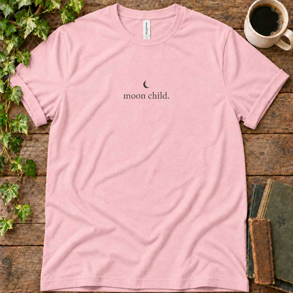 Pink regular-fit tee printed with moon child, flat lay on rustic wood with ivy, coffee and vintage books