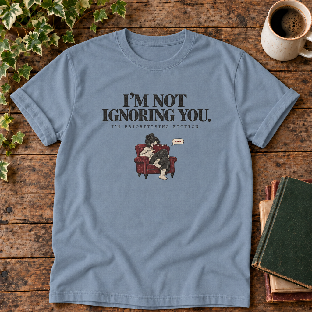I'm not ignoring you t-shirt in Blue Jean, flat lay on dark rustic wood with ivy, coffee mug and green-over-red-and-tan book pile
