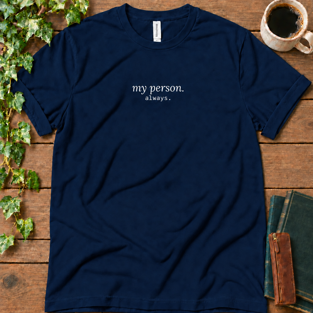 Navy regular-fit tee printed with my person. always., flat lay on rustic wood with ivy, coffee and vintage books