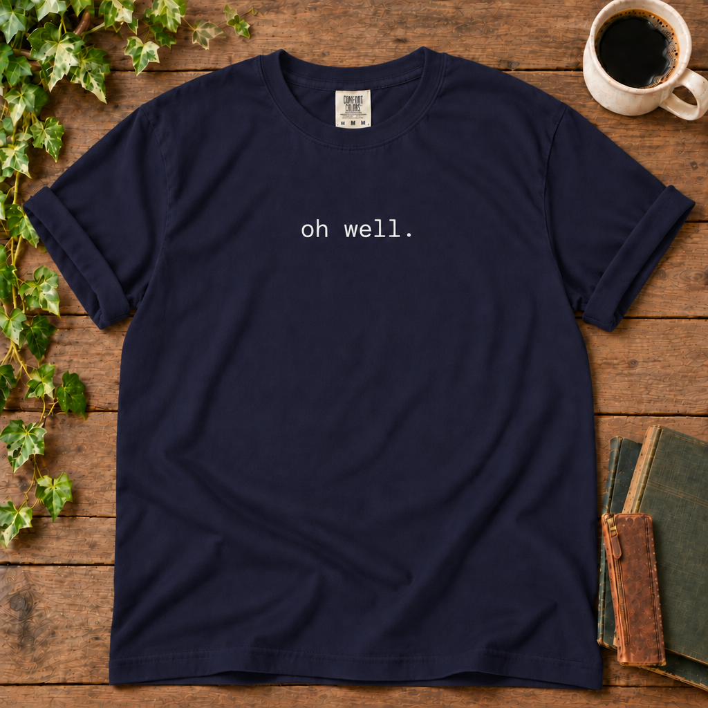 True navy relaxed-fit tee printed with oh well., flat lay on rustic wood with ivy, coffee and vintage books