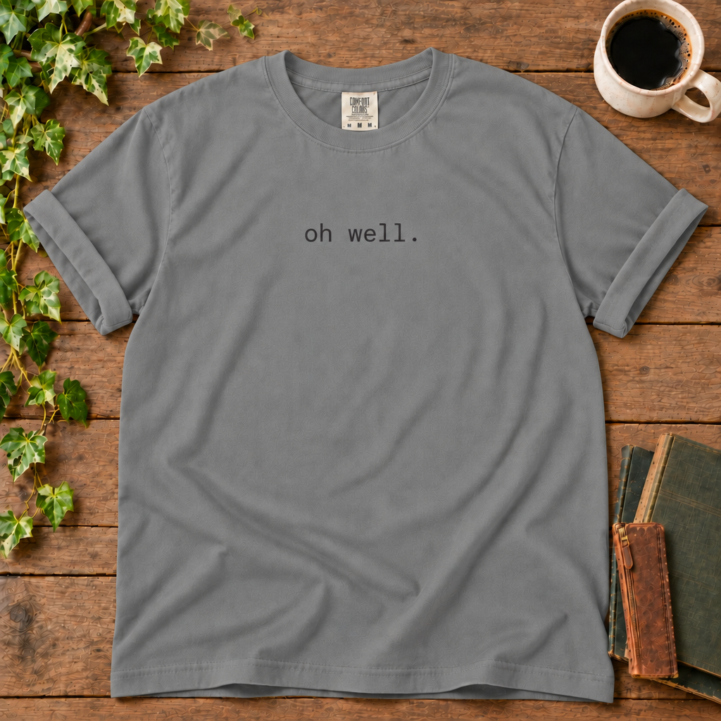 Grey relaxed-fit tee printed with oh well., flat lay on rustic wood with ivy, coffee and vintage books