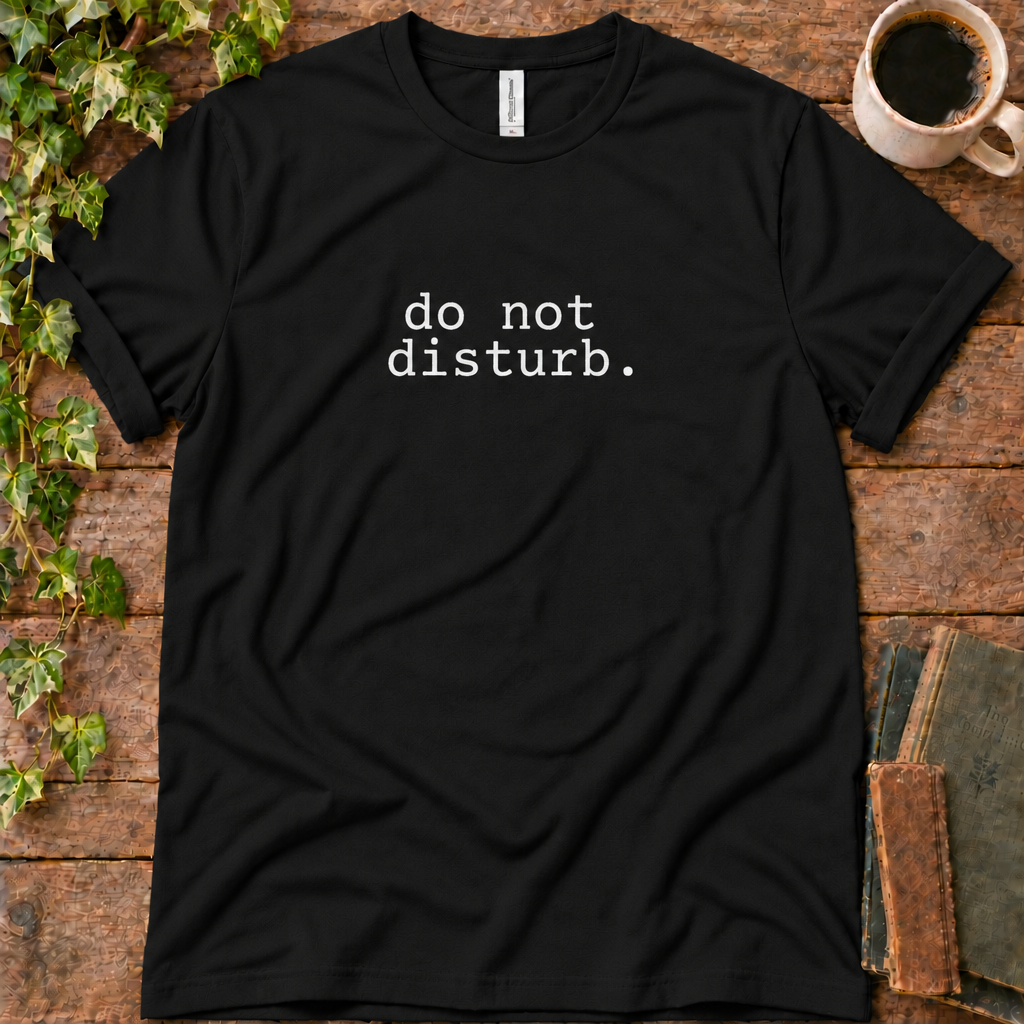 Black regular-fit tee printed with do not disturb, flat lay on rustic wood with ivy, coffee and vintage books