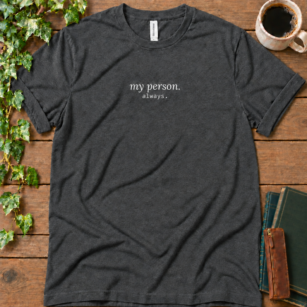 Dark grey heather regular-fit tee printed with my person. always., flat lay on rustic wood with ivy, coffee and vintage books