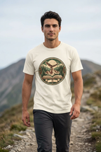 Young adult man hiking on a mountain trail wearing the mountain adventure vintage t-shirt in Ivory, with a minimal blurred mountain background