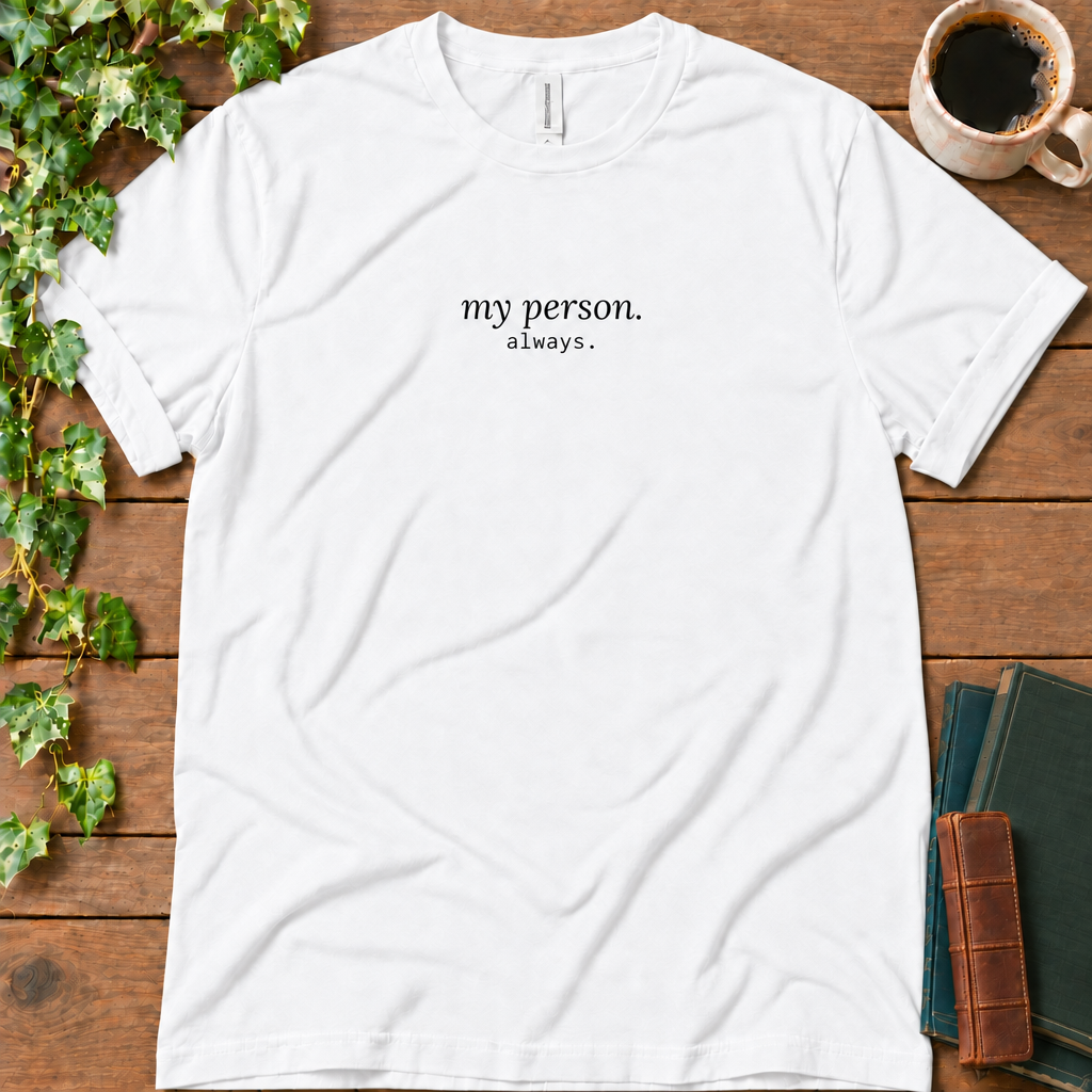 White regular-fit tee printed with my person. always., flat lay on rustic wood with ivy, coffee and vintage books