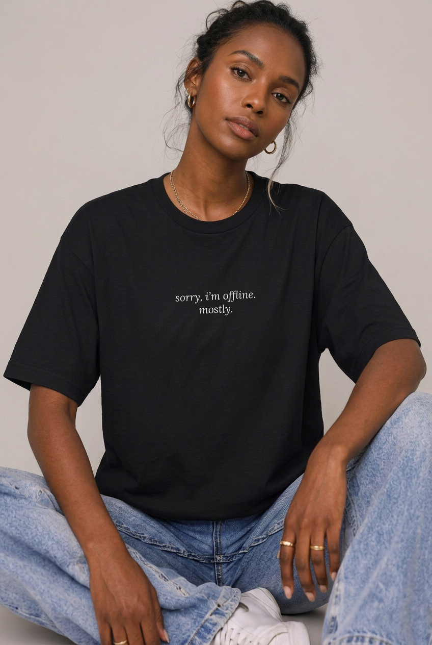 Woman wearing Black sorry I'm offline mostly t-shirt, seated editorial lifestyle