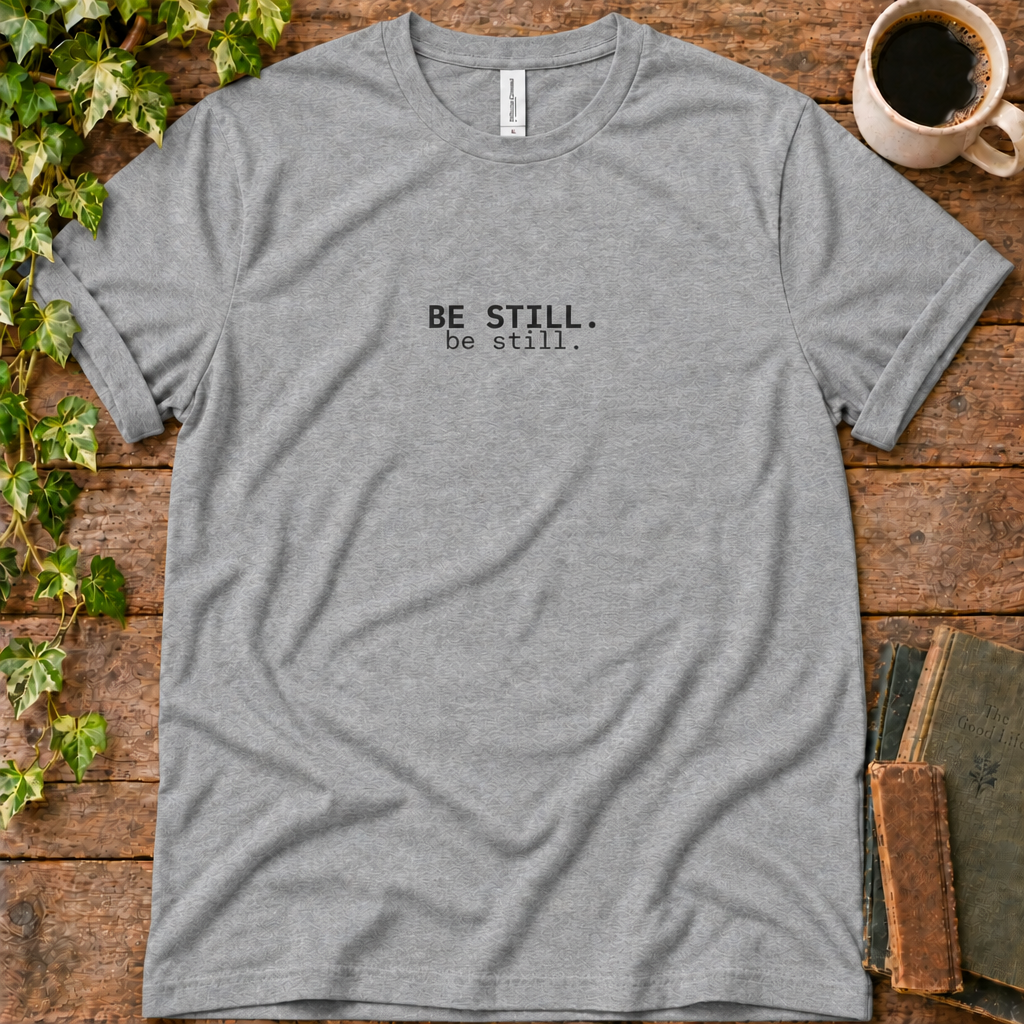 Athletic heather regular-fit tee printed with be still, flat lay on rustic wood with ivy, coffee and vintage books