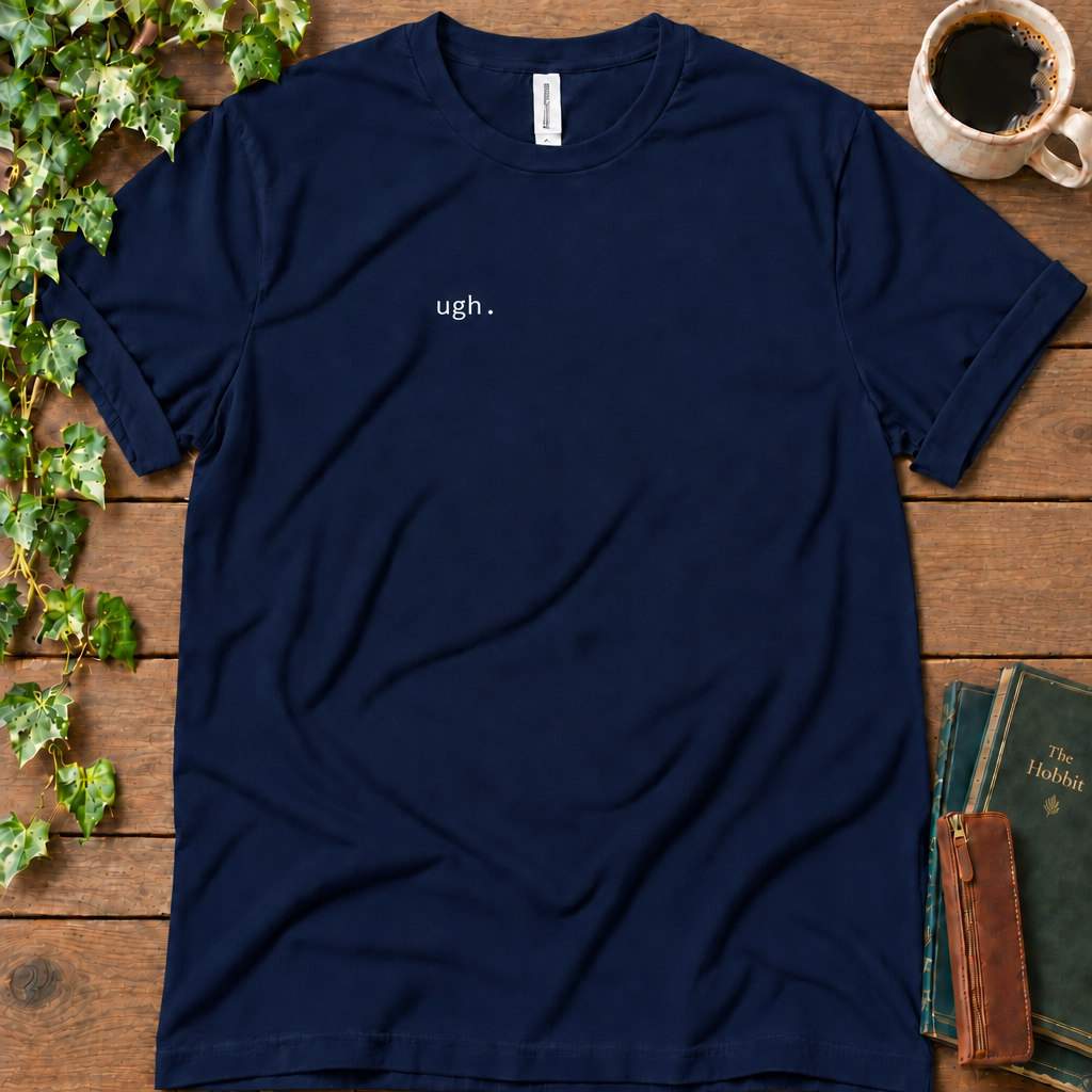 Navy regular-fit tee printed with ugh. on the left chest, flat lay on rustic wood with ivy, coffee and vintage books