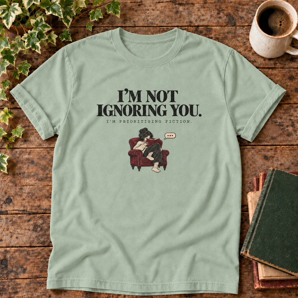 I'm not ignoring you t-shirt in Bay, flat lay on dark rustic wood with ivy, coffee mug and green-over-red-and-tan book pile