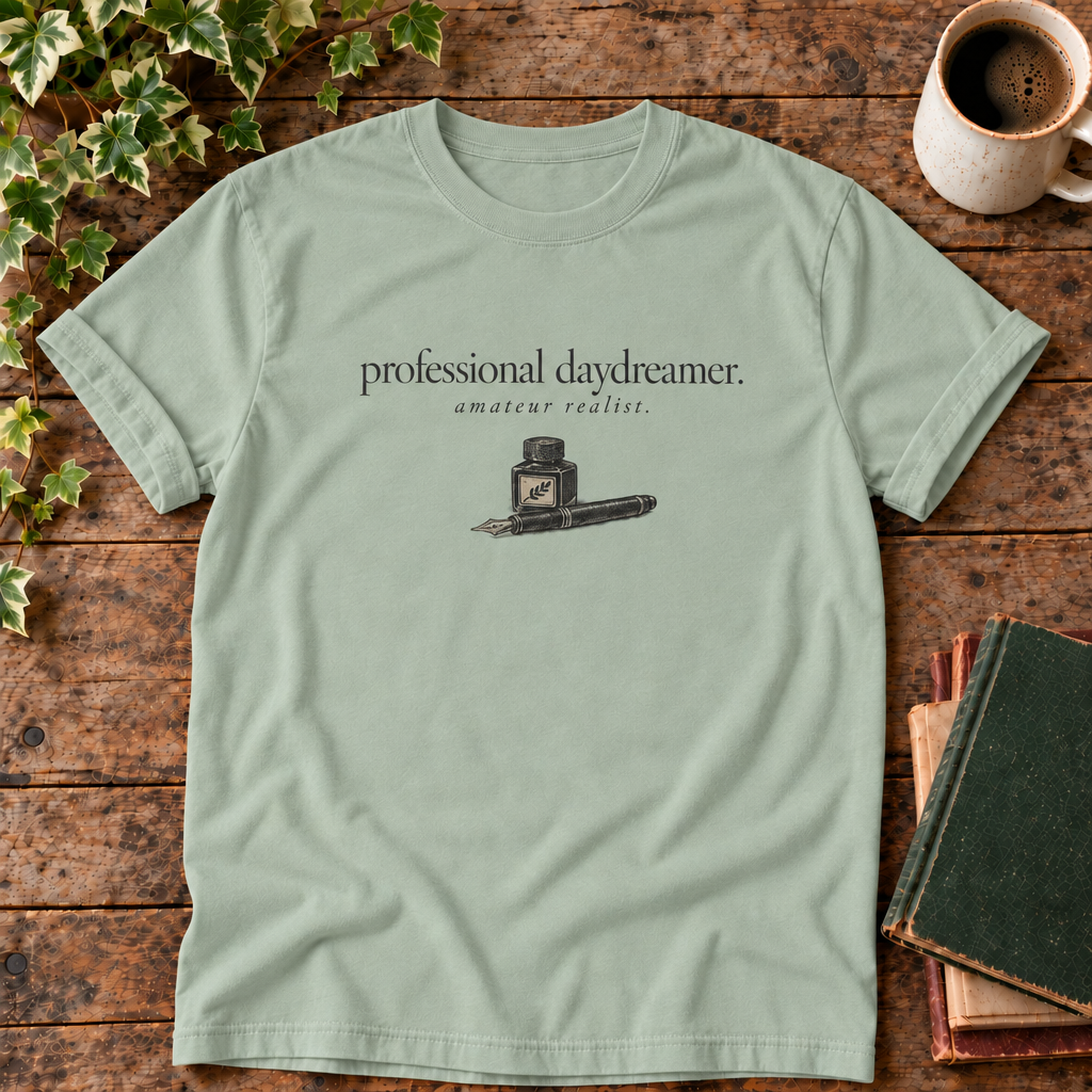 professional daydreamer t-shirt in Bay, flat lay on dark rustic wood with ivy, coffee mug and green-over-red-and-tan book pile