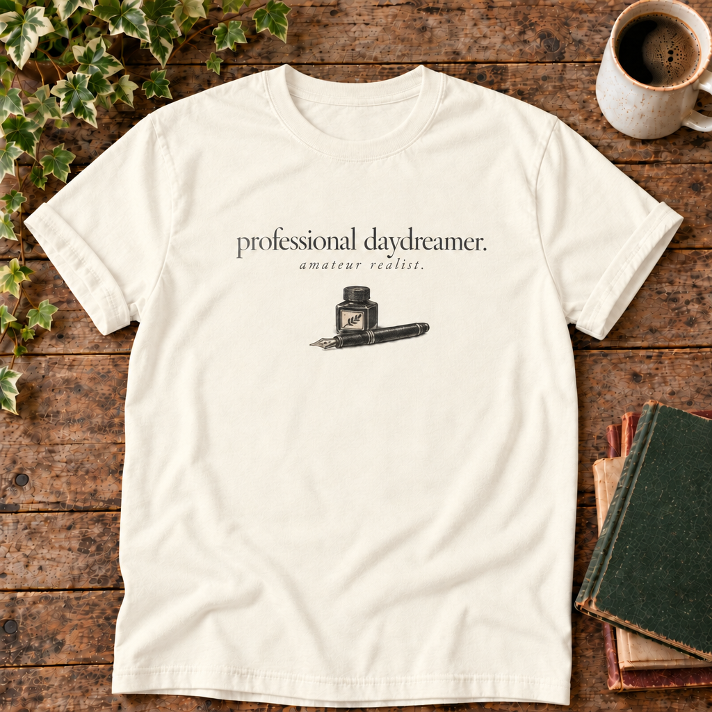 professional daydreamer t-shirt in Ivory, flat lay on dark rustic wood with ivy, coffee mug and green-over-red-and-tan book pile