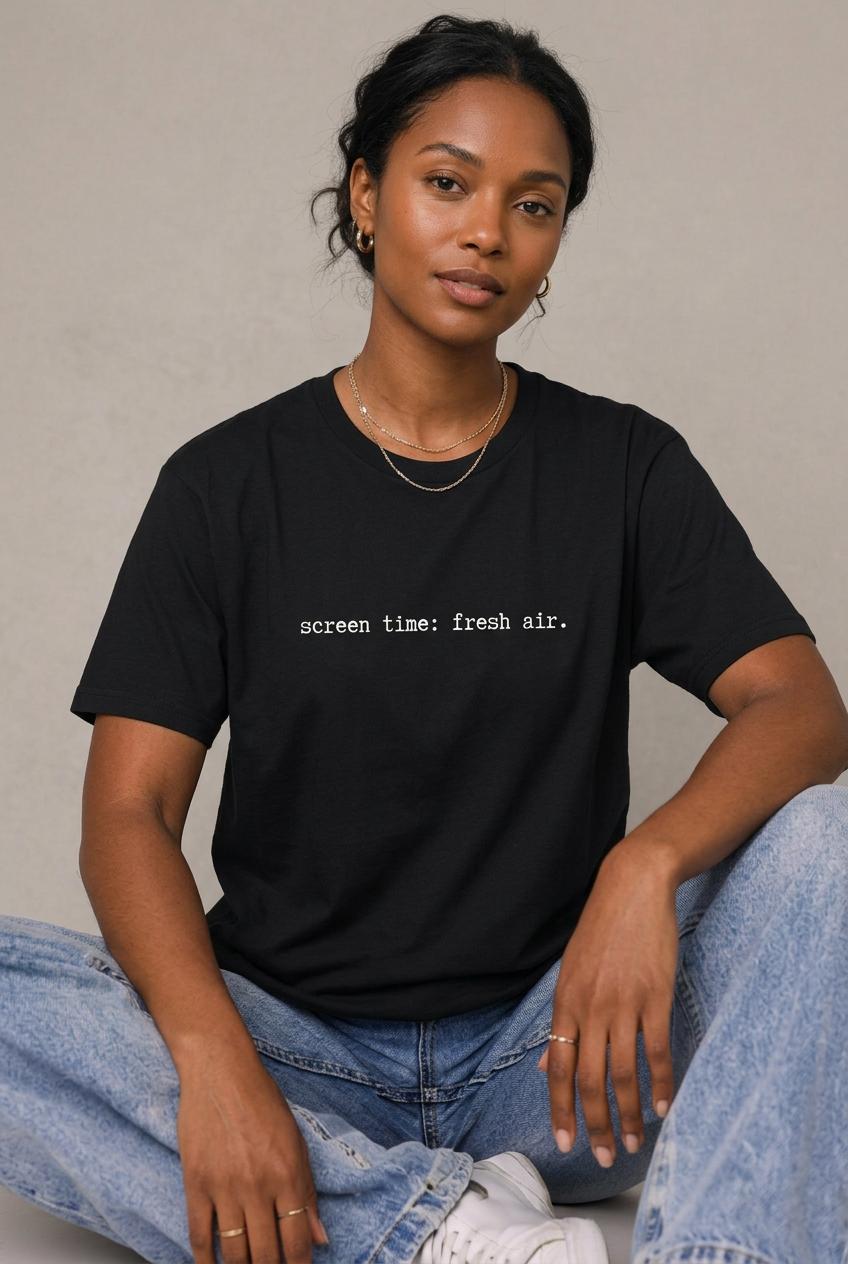 Woman wearing Black screen time fresh air t-shirt, seated editorial lifestyle